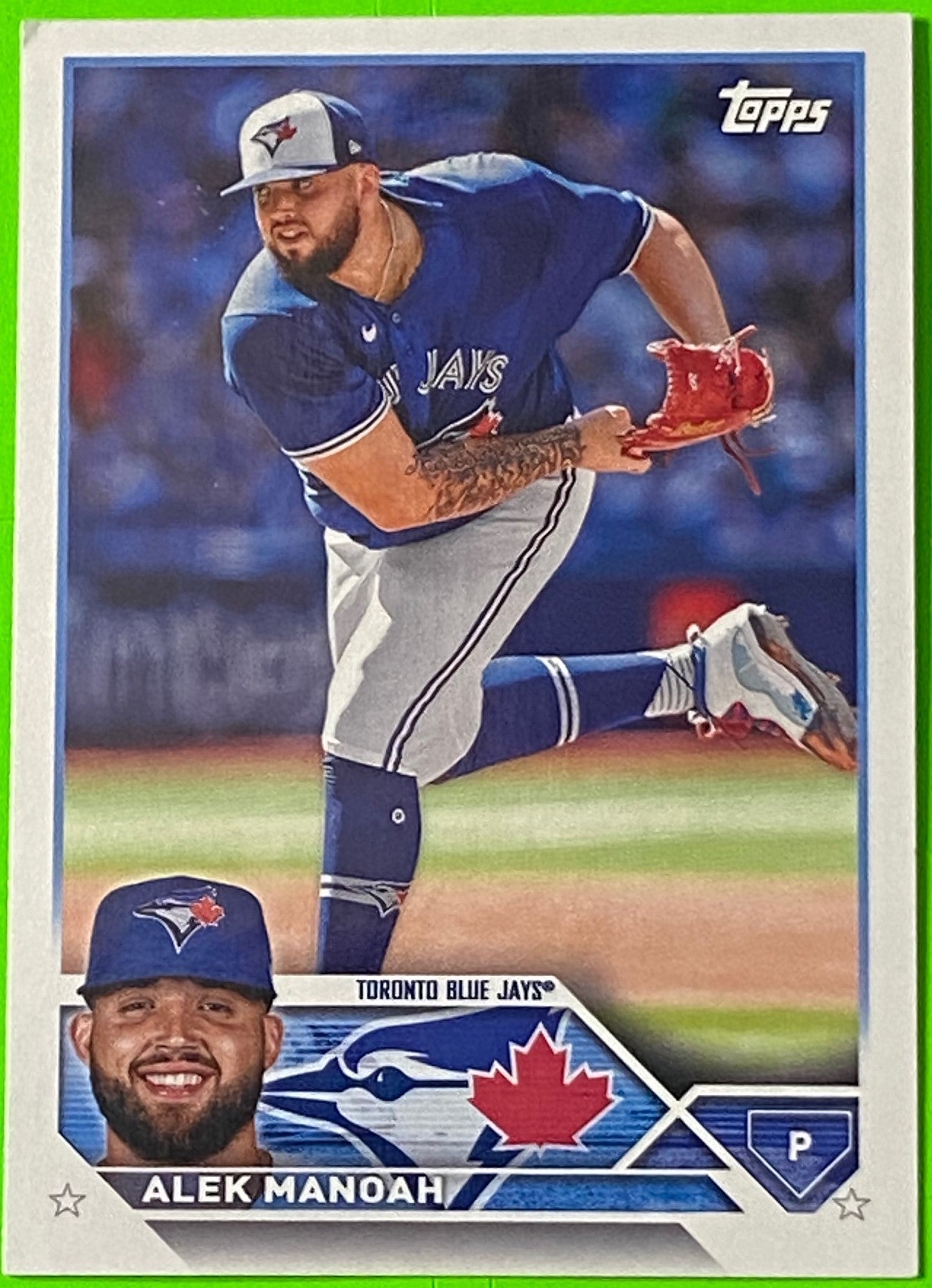 A collectible baseball card featuring Alek Manoah of the Toronto Blue Jays in mid-pitching action, with team colors and logo.